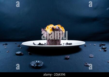 Schokolade, Rosinen-Chips und Schokolade Rosinen-Muffin auf einem weißen Teller. Schwarzer Hintergrund. Stockfoto