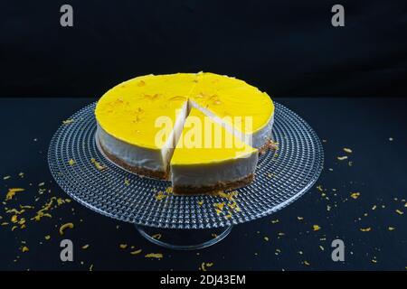 Geschnitten ​​lemon Käsekuchen auf Glasplatte auf schwarzem Hintergrund. Stockfoto