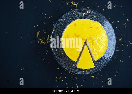 Geschnitten ​​lemon Käsekuchen auf Glasplatte auf schwarzem Hintergrund. Stockfoto