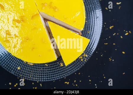 Geschnitten ​​lemon Käsekuchen auf Glasplatte auf schwarzem Hintergrund. Stockfoto