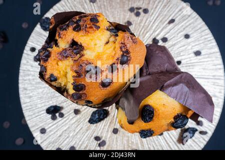 Schokolade, Rosinen-Chips und Schokolade Rosinen-Muffin auf einem weißen Teller. Schwarzer Hintergrund. Copyspace Stockfoto