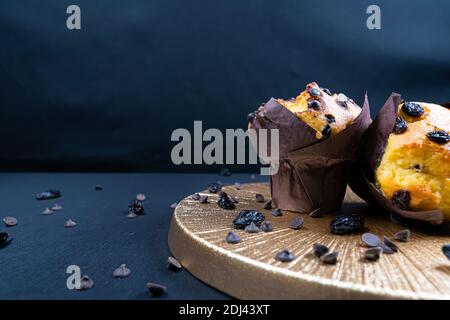 Schokolade, Rosinen-Chips und Schokolade Rosinen-Muffin auf einem weißen Teller. Schwarzer Hintergrund. Copyspace Stockfoto