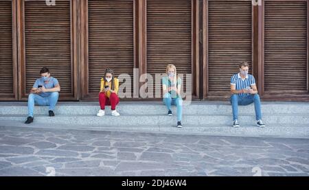 Multirassische Gruppe von Freunden tragen schützende Gesichtsmaske während der Verwendung Handy im Freien - Social distance Konzept Stockfoto