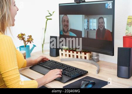 Fröhliche junge Frau mit Videoanruf am Computer mit Freunden - Fokus auf Stockfoto