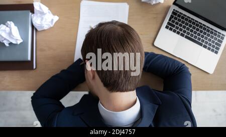 Draufsicht überarbeiteter müder Geschäftsmann, der Anzug trägt und am Arbeitsplatz schläft Stockfoto