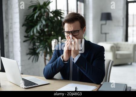 Ungesunde junge Geschäftsmann weht laufende Nase, hält Papier Serviette Stockfoto