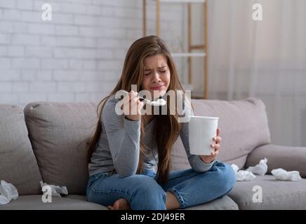 Traurige Millennial Dame weinend und Eis essen, während sie zuschaute Romantischer Film nach der Trennung Stockfoto