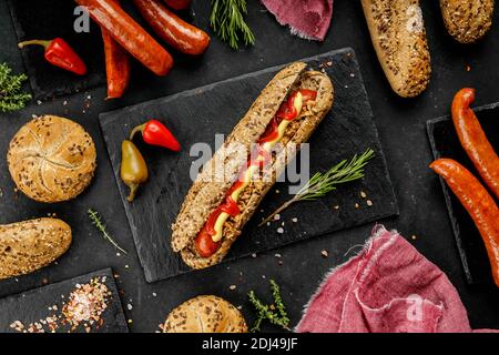 Flach Lay Zusammensetzung von leckeren Hot Dogs und Sandwiches mit Verschiedene Beläge auf dem dunklen Hintergrund Stockfoto