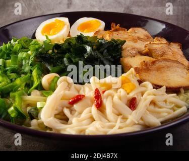 Eine Nahaufnahme eines köstlichen Ramen Gericht in einem schwarzen Schüssel Stockfoto