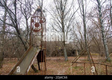 Beängstigender und verlassener Spielplatz in einem Dorf in der Nähe von Pripyat, einer Geisterstadt im Tschernobyl-Sperrgebiet. Stockfoto