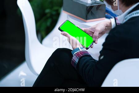 Asiatische Person Hand hält Smartphone mit leeren Touchscreen-Display. Menschen sitzen und verwenden Mobiltelefon für die Kommunikation in Unternehmen und Unternehmen. Stockfoto