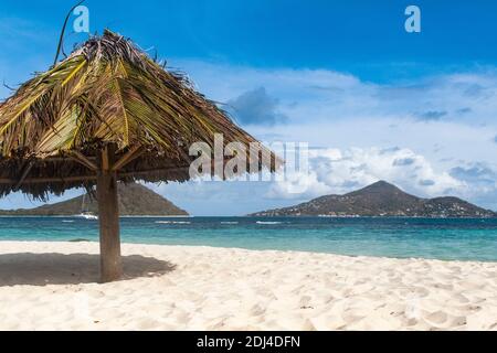 Karibikblick von der Insel Mopian: Sonnenschirm, Sandstrand, Inseln Petit Martinique und Petit Saint Vincent: Saint Vincent und die Grenadinen. Stockfoto