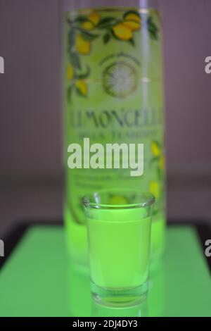 Glas und Flasche Limoncello auf hellblauem Hintergrund Stockfoto