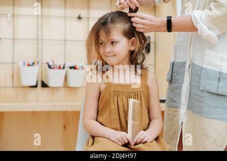 Mama macht Zöpfe für ihre Tochter im Kinderzimmer Stockfoto