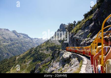 Touristenzug voller Menschen, die durch eine Bergschlucht in den Pyrenäen laufen, Artouste France, Rückansicht Stockfoto