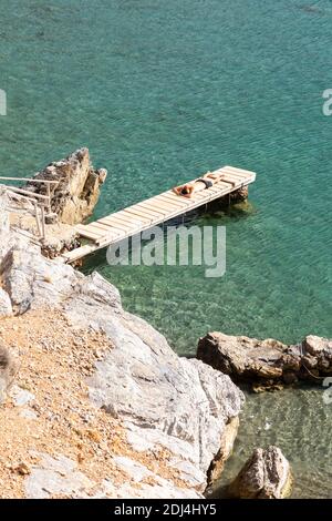 Ein Mann, der auf einem kleinen hölzernen Pier am Preveli Beach, Kreta, Griechenland, Sonnenbaden geht Stockfoto