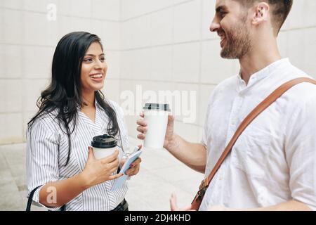 Glückliche junge Geschäftsleute, die beim Kaffee über Neuigkeiten und Klatsch sprechen Pause Stockfoto