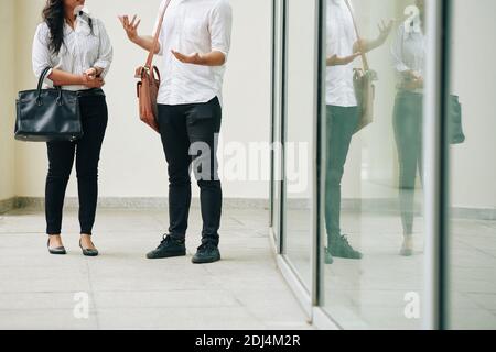 Beschnittenes Bild von jungen Geschäftsleuten, die vor dem Bürogebäude stehen Und über wichtige Themen zu sprechen Stockfoto