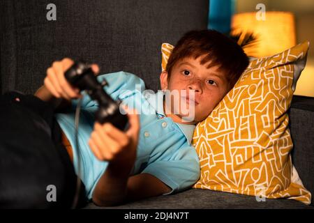 Allein junges Kind spielen Videospiel mit Joystick während spät Nacht während des Schlafens auf dem Bett - Konzept der Kinder Spiel Sucht und spät in die Nacht spielen Spiel Stockfoto