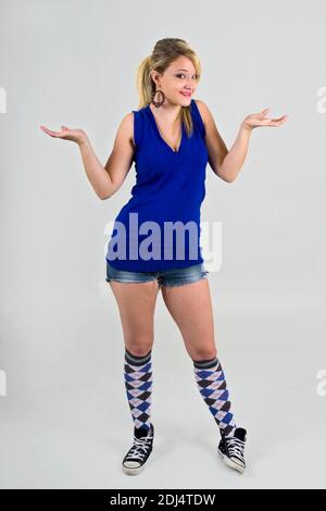 Junge blonde weibliche Teenager in blau casual top zuckt sie Schultern Stockfoto