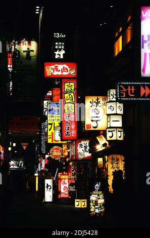 Neonlichter und Reklametafeln auf der Straße in Osaka, Japan. Kontrastreiches Nahnbild mit leuchtenden Ladenschildern Stockfoto