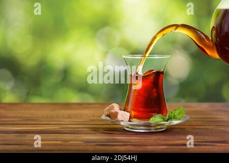 Tee aus der Teekanne in Glas gießen Stockfoto