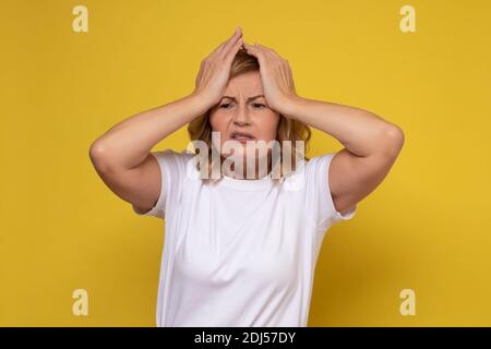 Ältere Frau, die an Kopfschmerzen leidet, verzweifelt und gestresst, weil Schmerzen und Migräne die Hände am Kopf halten. Stockfoto
