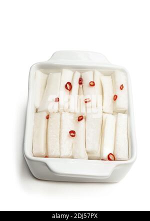 Marinierte Daikon-Scheibe mit Gewürzen in Tonschüssel isoliert auf Weiß Stockfoto