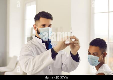 Arzt bereitet Spritze für die Impfung gegen COVID-19 für junge Schwarzer Patient Stockfoto