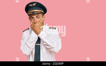 Schöner Mann mit Bart tragen Flugzeug Pilot Uniform schockiert Abdeckung Mund mit Händen für Fehler. Secret Konzept. Stockfoto