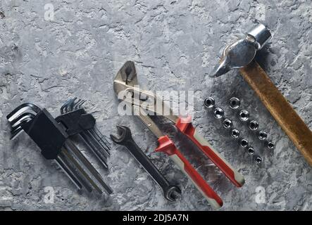Arbeitswerkzeug auf einem grauen Betonhintergrund. Schraubenschlüssel, Hammer, Sechskantschlüssel. Draufsicht, Kopierbereich. Stockfoto