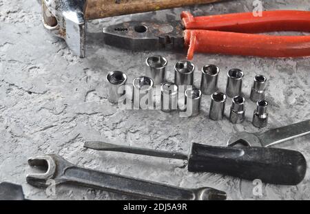Arbeitswerkzeug auf einem grauen Betonhintergrund. Schraubenschlüssel, Hammer, Schraubendreher, Zange. Draufsicht, Kopierbereich. Stockfoto