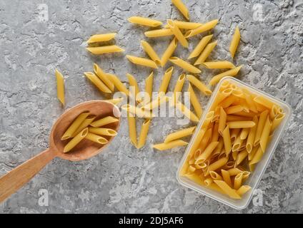 Kleben Sie in den hölzernen Löffel und in den Behälter auf den grauen Betontisch auf. Stockfoto