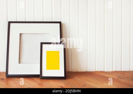 Zwei Poster auf dem Holzboden durch die weisse Wand mit Kopie Raum Stockfoto