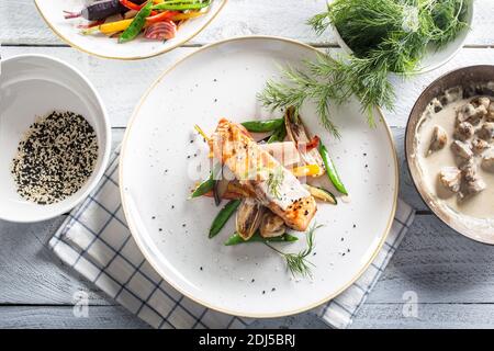 Draufsicht auf einen gesunden gedünsteten Lachs Fisch und Gemüse neben Kräutern und Pilzsoße. Stockfoto