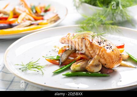 Gesund gekochter norwegischer Lachs serviert mit gegrilltem Gemüse und Pilzen. Stockfoto