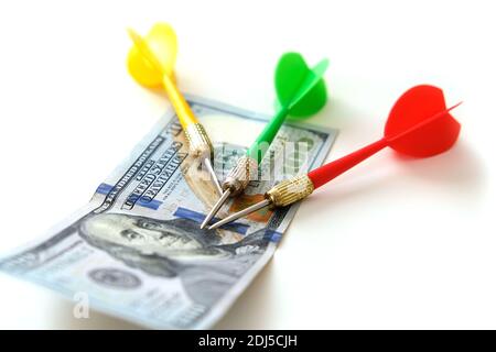 Investieren mit Darts in gelb, grün und rot auf weißem Hintergrund und 100 US-Dollar und Dollar für eine genaue Investition, Stockfoto