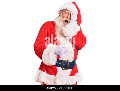 Alter älterer Mann mit grauen Haaren und langem Bart trägt traditionelle weihnachtsmann Kostüm gähnend müde Abdeckung halb Gesicht, Auge und Mund mit Hand. Gesicht h Stockfoto