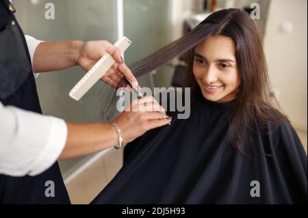 Friseur mit Schere schneidet Frauenhaare Stockfoto