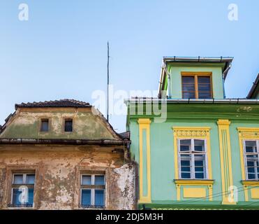 Zwei nebeneinander alte mittelalterliche Gebäude in Sighisoara, Rumänien. Restauriertes Gebäude neben einem abgenutzten, unrestaurierten Gebäude. Stockfoto