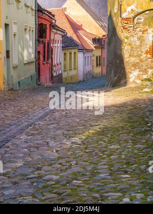 Bunte Szene mit Kopfsteinpflasterstraßen und alten Gebäuden der mittelalterlichen Festung Sighisoara, in Rumänien. Stockfoto