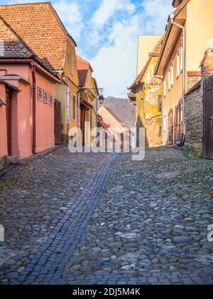 Bunte Szene mit Kopfsteinpflasterstraßen und alten Gebäuden der mittelalterlichen Festung Sighisoara, in Rumänien. Stockfoto