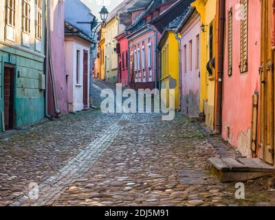 Bunte Szene mit Kopfsteinpflasterstraßen und alten Gebäuden der mittelalterlichen Festung Sighisoara, in Rumänien. Stockfoto