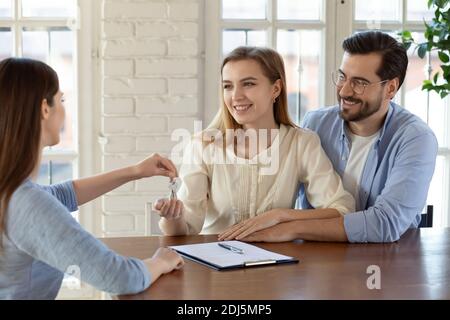 Makler geben Schlüssel zu aufgeregt paar Käufer Stockfoto