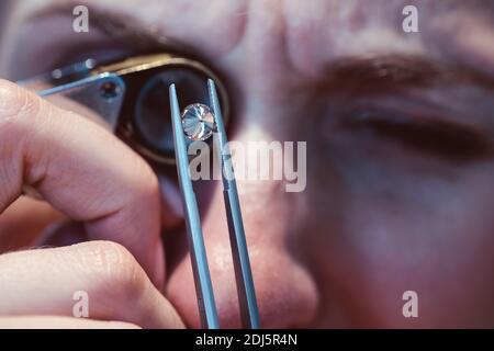 Juwelier schaut durch eine Lupe auf Edelstein Stockfoto