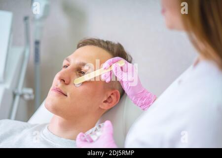 Männliche Kosmetik. Ein gut aussehender Mann, der im luxuriösen Spa eine Gesichtsbehandlung bekommt Stockfoto