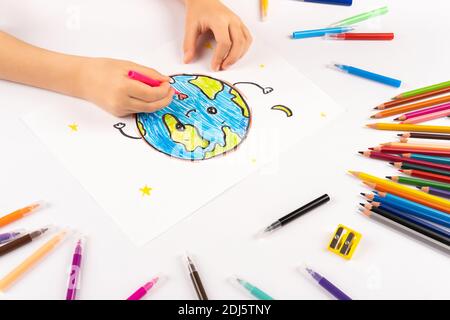 Kind Mädchen zeichnet Planeten Erde auf einem weißen Blatt. Stockfoto