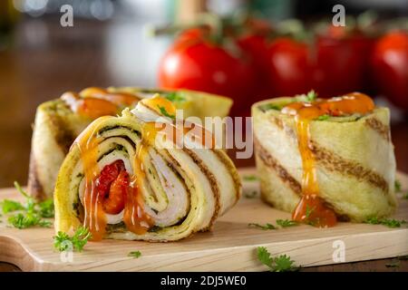 Tapas-Wrap mit Huhn, Pesto und Paprika auf Holz Schneidebrett mit Kräutern Stockfoto