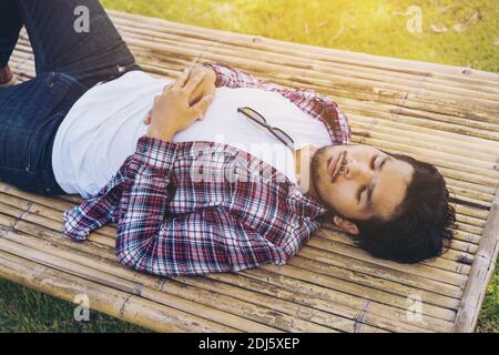 Junger Mann schläft auf Bambusbett, Sitz, Tisch oder Sonnenliege aus Naturmaterial. Natur, Entspannung und Schlaf gut-Konzept. Tagträumer ist Tagträumen Stockfoto