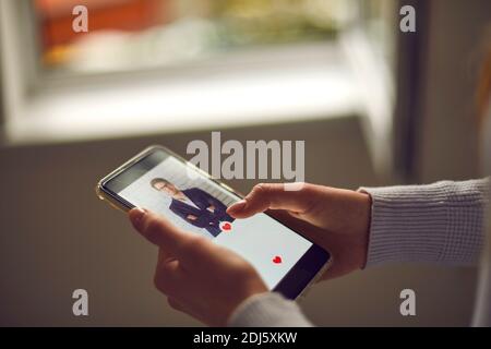 Nahaufnahme einer Frau, die ein rotes Herz in Sympathie für einen Mann drückt, der auf dem Bildschirm erscheint. Stockfoto